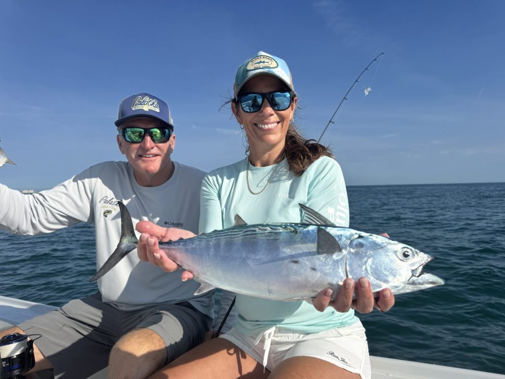 Two anglers holding large redfish on a fishing boat