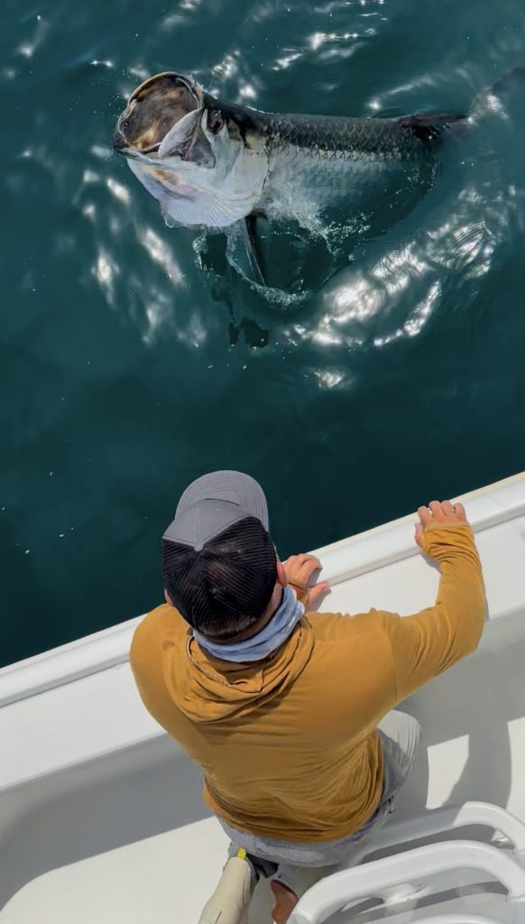 Angler fighting a large fish in clear coastal water